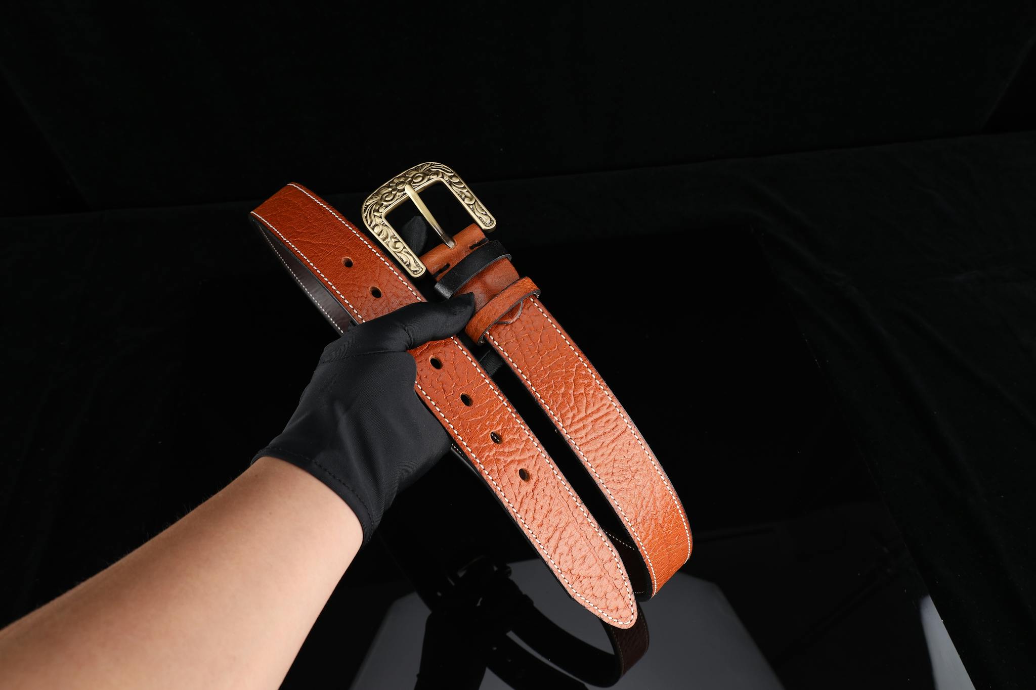 Close-up of a luxury leather belt with ornate brass buckle, ideal for fashion or gift.